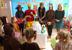Zaproszeni goście i dzieci przy torcie urodzinowym
